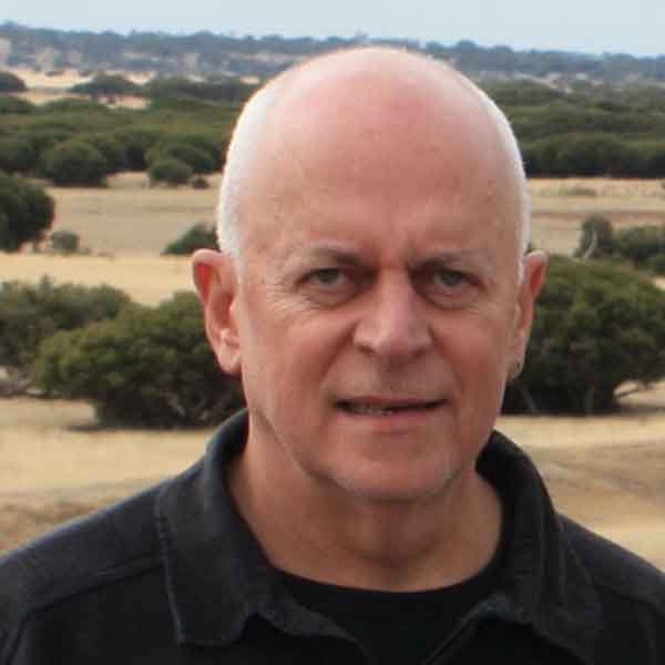 Headshot portrait of eminent journalist, academic, and Walkley Award winner Chris Nash outdoors against a rural landscape backdrop.